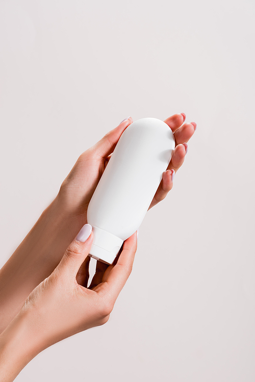 cropped view of woman holding tube of hand lotion isolated on grey