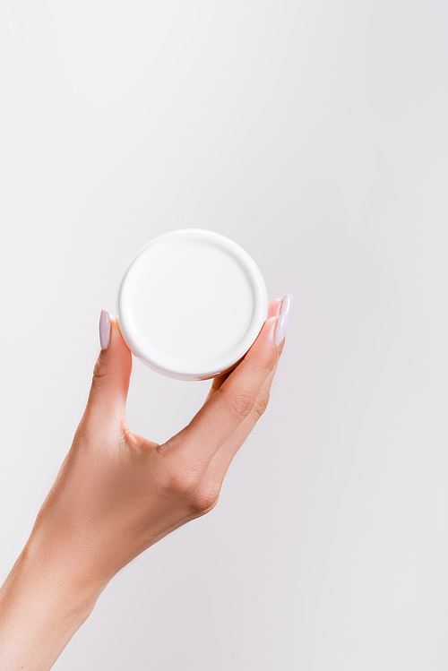 cropped view of woman holding container of hand cream isolated on grey