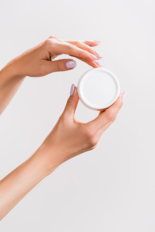 cropped view of woman holding container of hand cream isolated on grey
