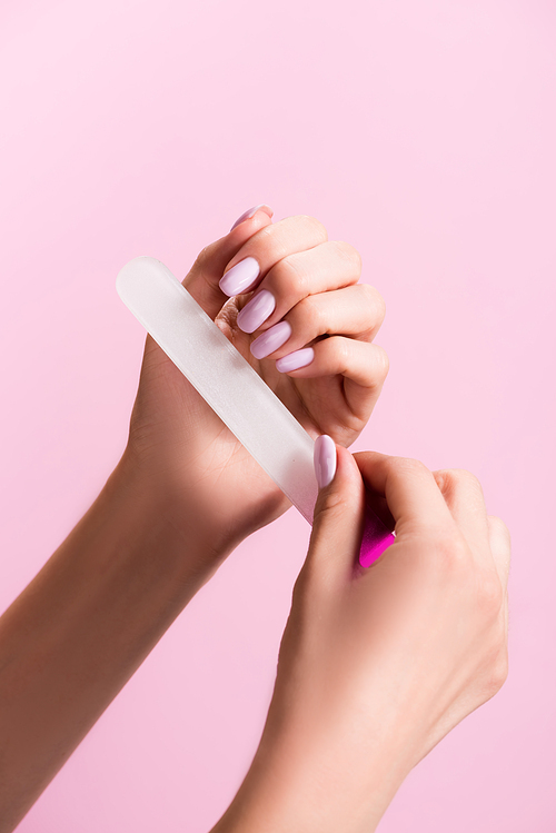 cropped view of woman using nail file isolated on pink