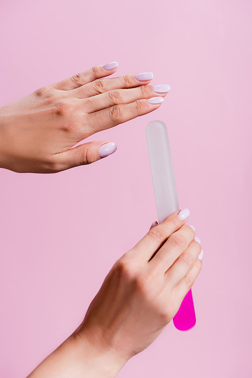 cropped view of woman holding nail file isolated on pink