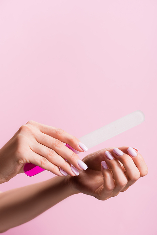 cropped view of woman using nail file isolated on pink