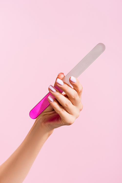 cropped view of woman holding nail file isolated on pink