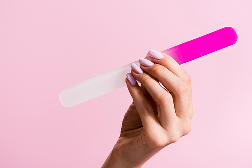 cropped view of woman holding nail file isolated on pink