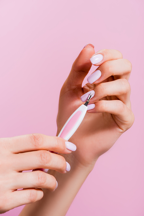 cropped view of woman using cuticle clipper isolated on pink