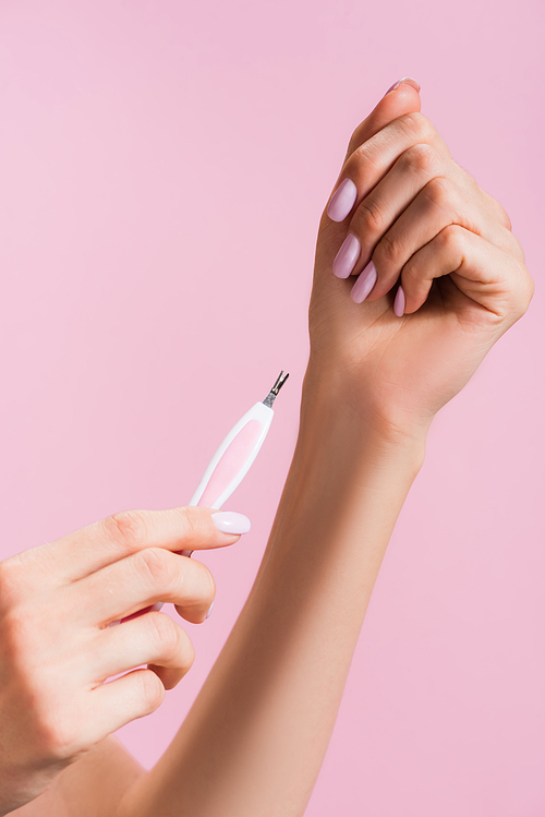 cropped view of woman using cuticle clipper isolated on pink