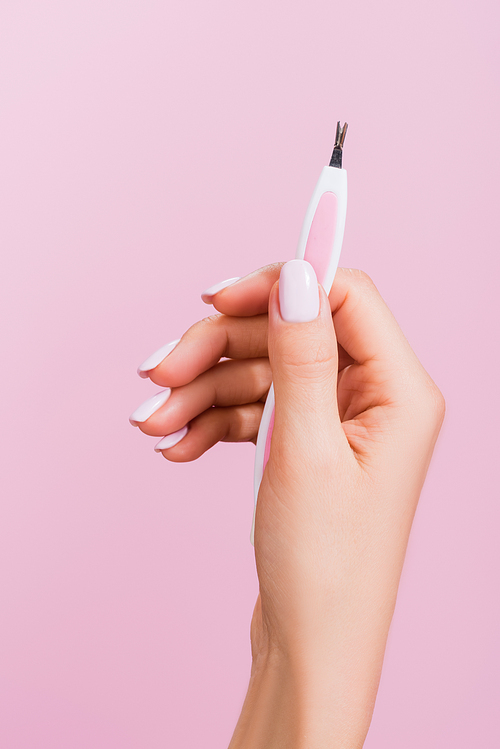 cropped view of woman holding cuticle clipper isolated on pink
