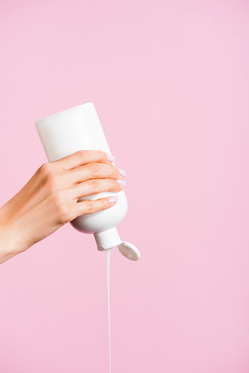 cropped view of woman squeezing lotion isolated on pink