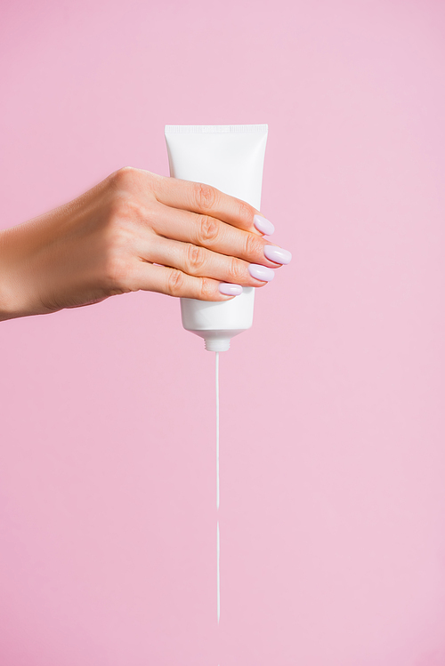 cropped view of woman squeezing hand cream isolated on pink