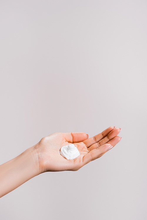 cropped view of woman showing hand cream isolated on grey