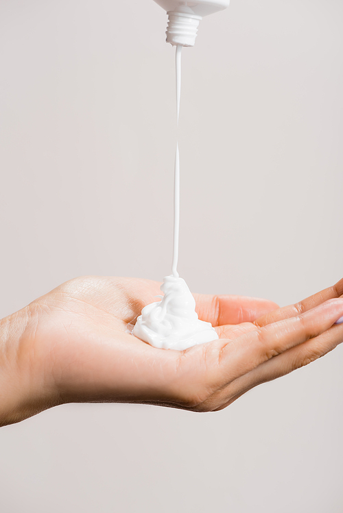 cropped view of woman squeezing hand cream isolated on grey