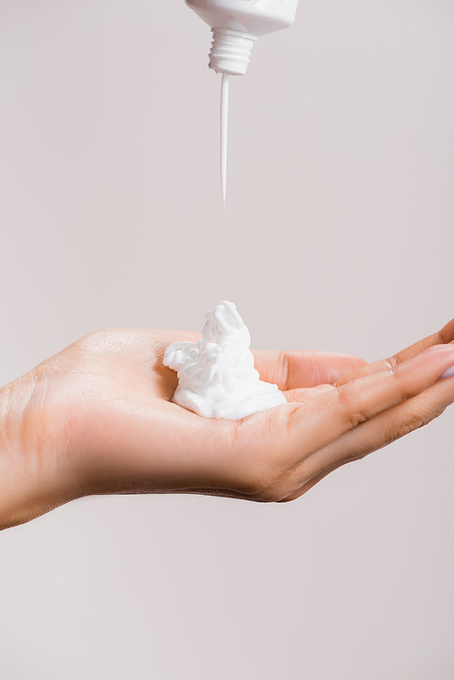 cropped view of woman squeezing hand cream isolated on grey