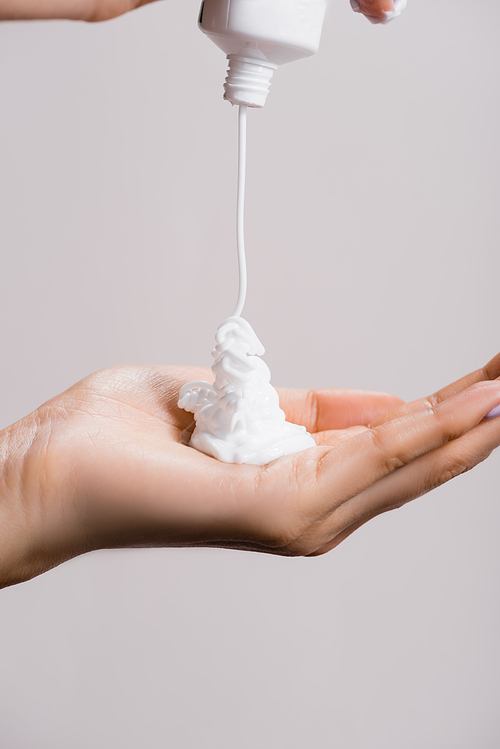 cropped view of woman squeezing hand cream isolated on grey