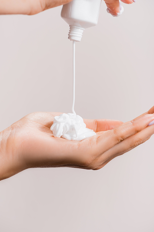 cropped view of woman squeezing hand cream isolated on grey