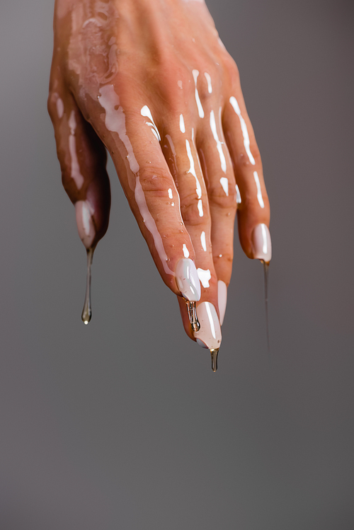 cropped view of female hand in honey isolated on grey