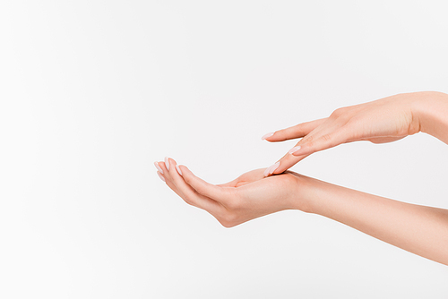 partial view of woman on woman touching hand while applying hand cream isolated on white