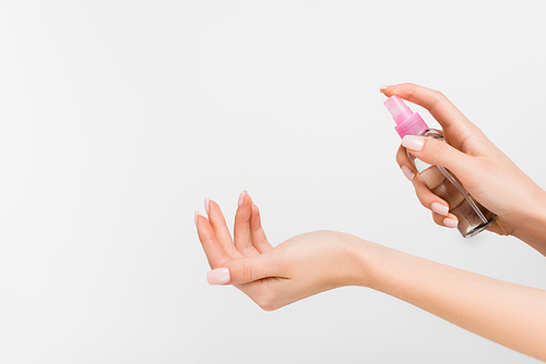 cropped view of woman holding spray bottle with liquid isolated on white