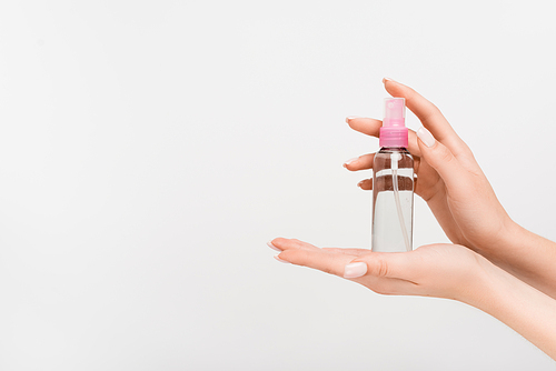 cropped view of woman holding spray bottle with aromatic mist in hands isolated on white