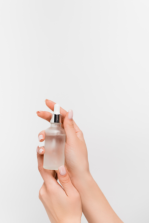 cropped view of woman holding bottle with serum isolated on white