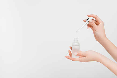 cropped view of woman holding bottle with serum and pipette isolated on white