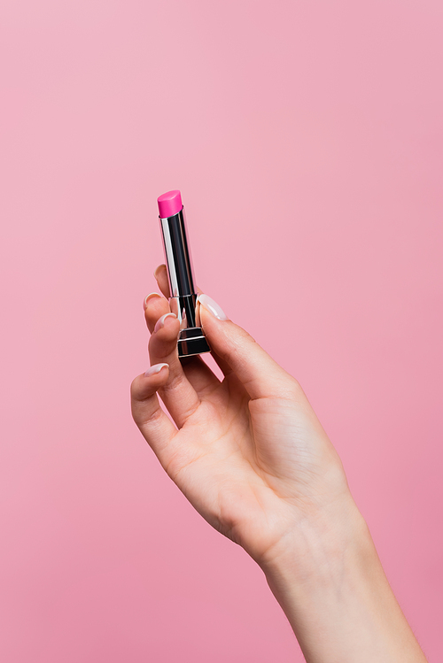 cropped view of woman holding lipstick in hand isolated on pink
