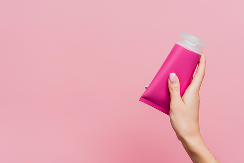 partial view of woman holding tube with lotion isolated on pink