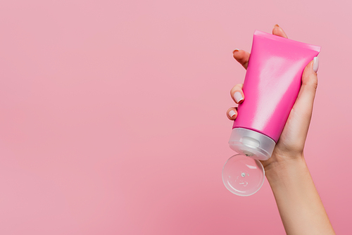 cropped view of woman holding tube with lotion isolated on pink