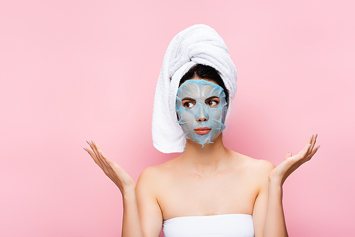 beautiful woman with mask sheet on face showing shrug isolated on pink
