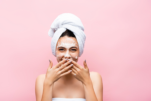 laughing beautiful woman with towel on hair and foam on face isolated on pink