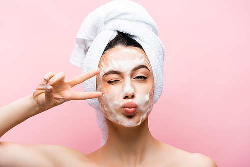 beautiful woman with towel on hair and foam on face grimacing isolated on pink