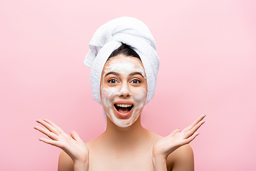 happy beautiful woman with towel on hair and foam on face isolated on pink