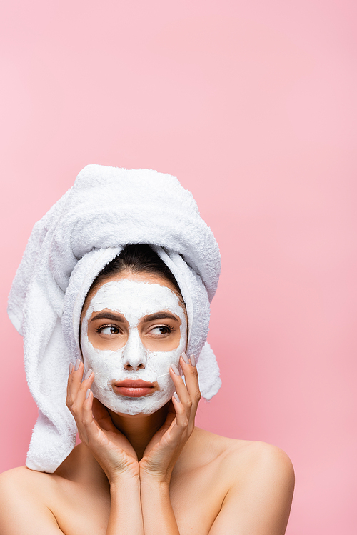 sad beautiful woman with towel on head and clay mask on face isolated on pink