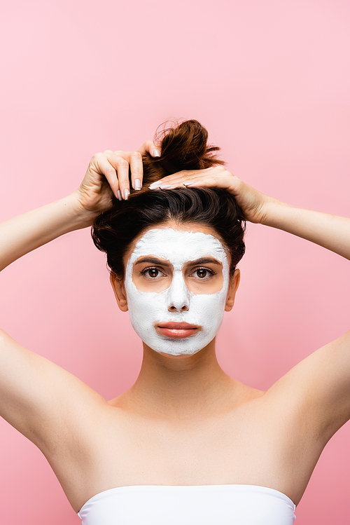 sad beautiful woman with clay mask on face isolated on pink