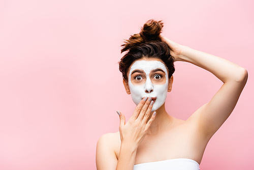 surprised beautiful woman with clay mask on face isolated on pink