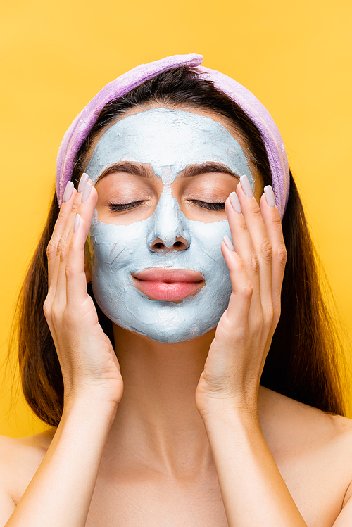 beautiful woman with clay mask on face and closed eyes isolated on yellow