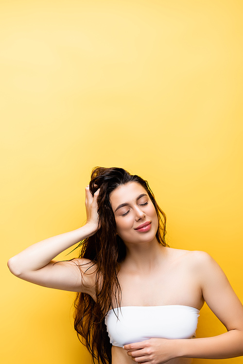 smiling beautiful woman with wet hair isolated on yellow