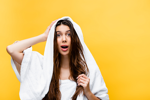 shocked beautiful woman with wet hair and towel isolated on yellow