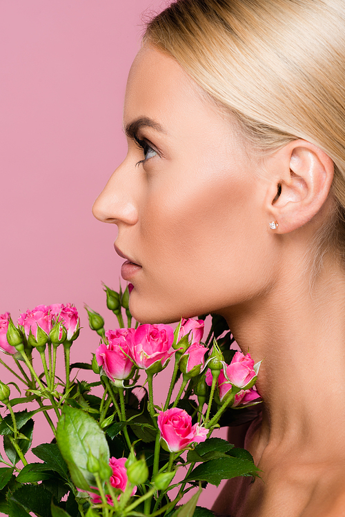 profile of beautiful blonde woman with rose bouquet isolated on pink