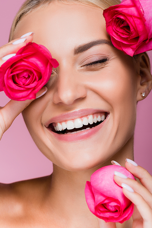smiling beautiful blonde woman with rose flowers isolated on pink