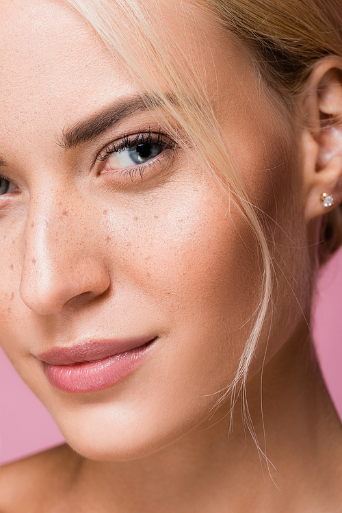 closeup of beautiful woman with freckles isolated on pink