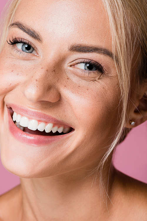 smiling beautiful blonde woman with freckles isolated on pink