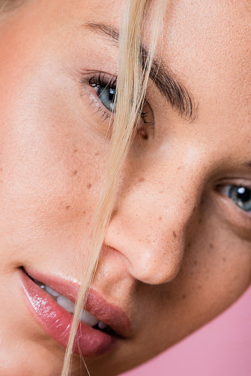 closeup of beautiful blonde woman with freckles isolated on pink
