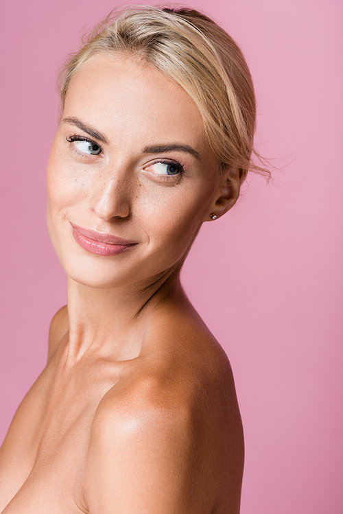 smiling beautiful blonde woman with freckles and bare shoulders isolated on pink