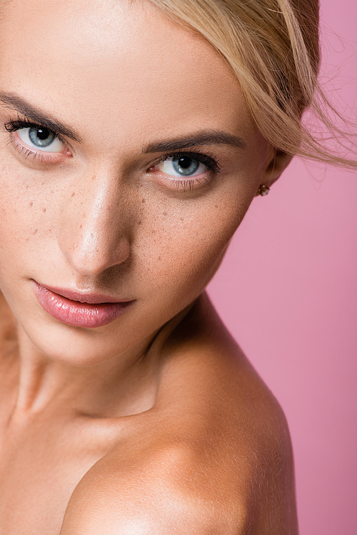 beautiful blonde woman with freckles and bare shoulders isolated on pink