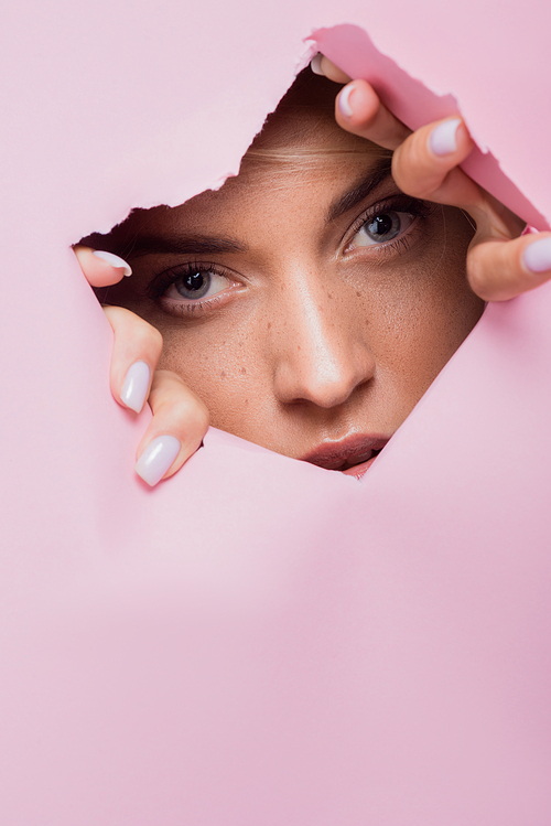 beautiful woman with freckles in pink paper hole