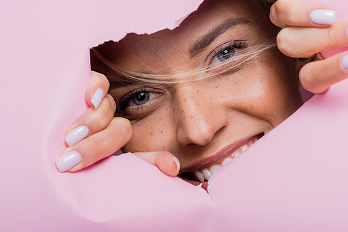 smiling beautiful woman with freckles in pink paper hole