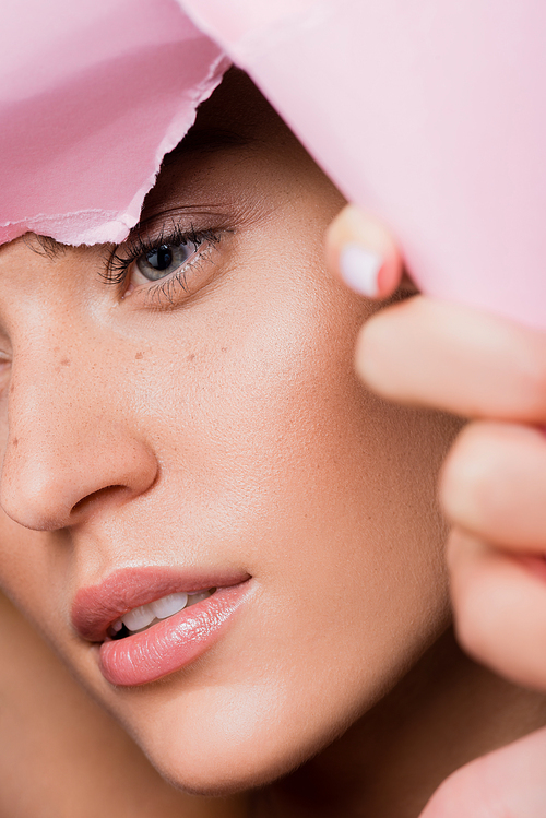 closeup of beautiful woman with freckles in pink paper hole