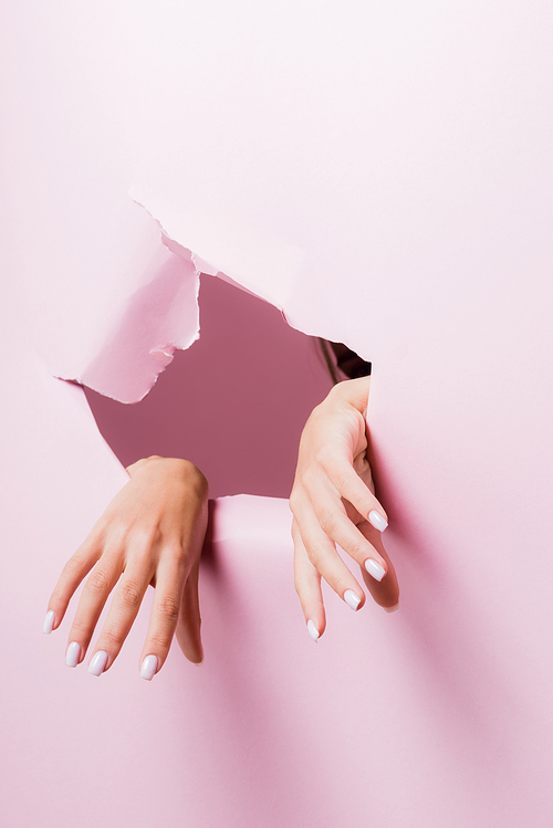 cropped view of female hands in pink paper hole