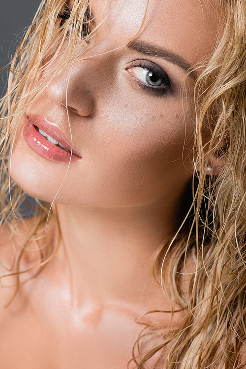 blonde woman with wet hair and freckles isolated on grey