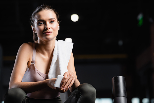 positive sportswoman  while holding mobile phone in sports center